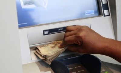 A woman takes Nigerian Naira from a bank's automated teller machine (ATM) in Ikeja district in the commercial capital Lagos